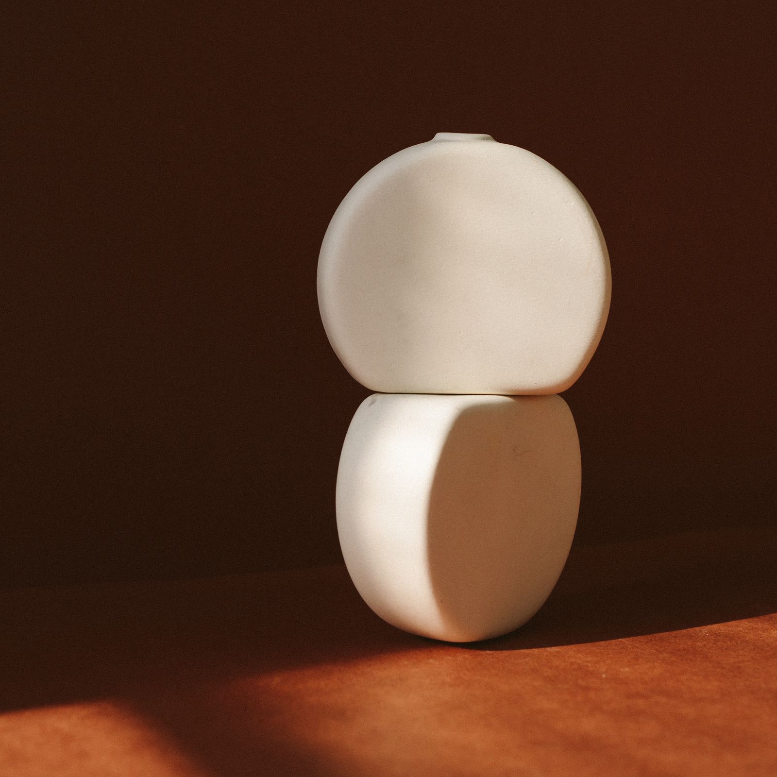 Rounded ceramic forms in warm directional light.