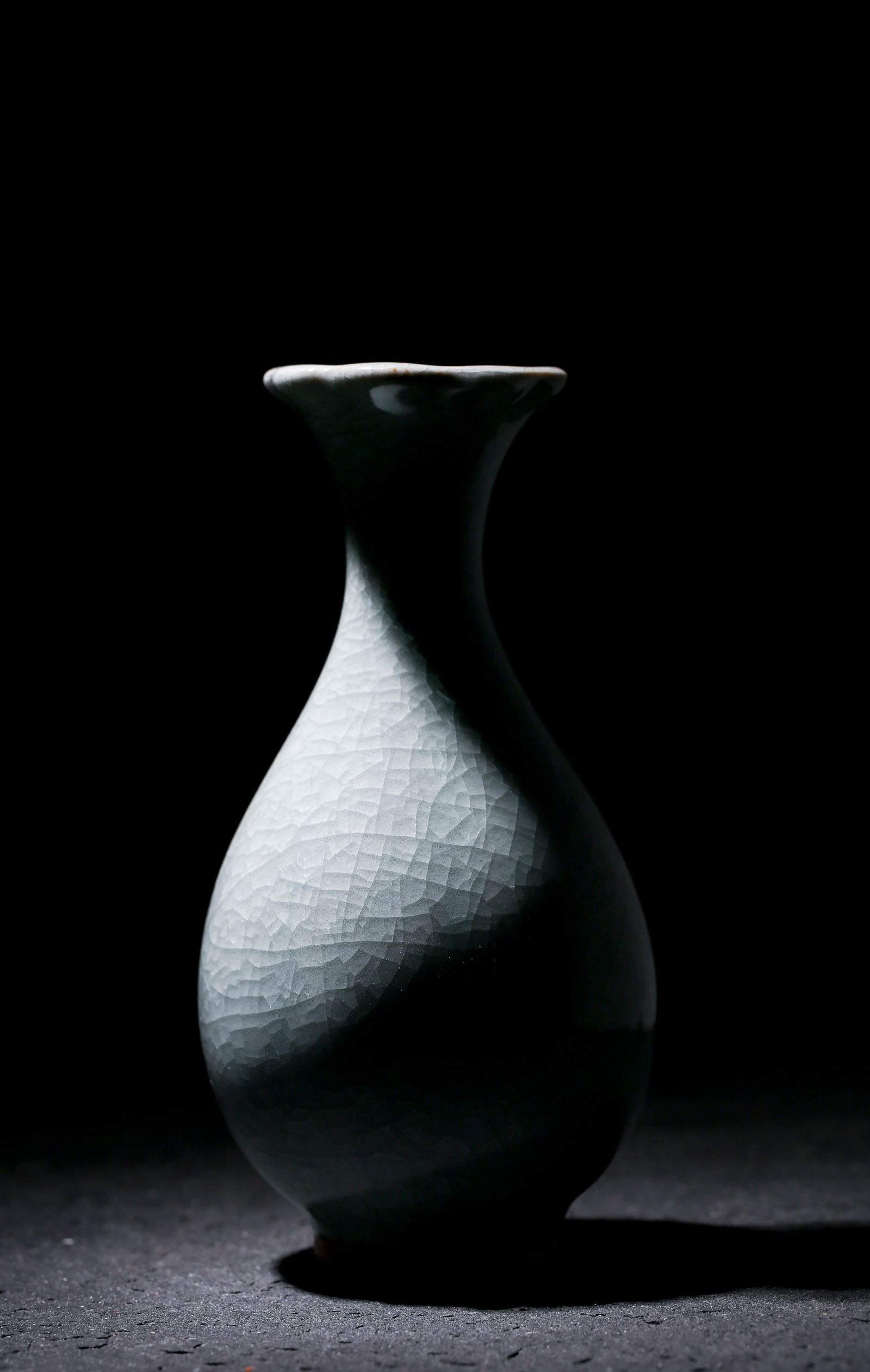 A black-and-white ceramic vase lit against a dark background.